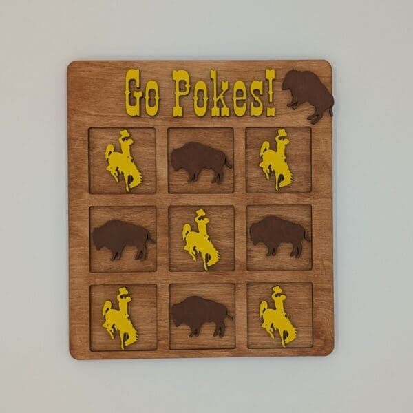 Red Rooster Laser Arts A wooden tic-tac-toe board with buffalo and cowboy rider pieces. “Go Pokes!” in yellow tops the board with a buffalo graphic—perfect to pair with your DIY Small Wooden Steamboat Home Sign.