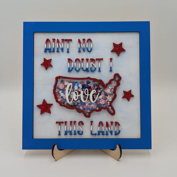 Red Rooster Laser Arts The DIY Patriotic Shaker Sign Kit - Love This Land features a blue border, bold red and blue AINT NO DOUBT! text, and three glittery red stars for a festive, framed look.