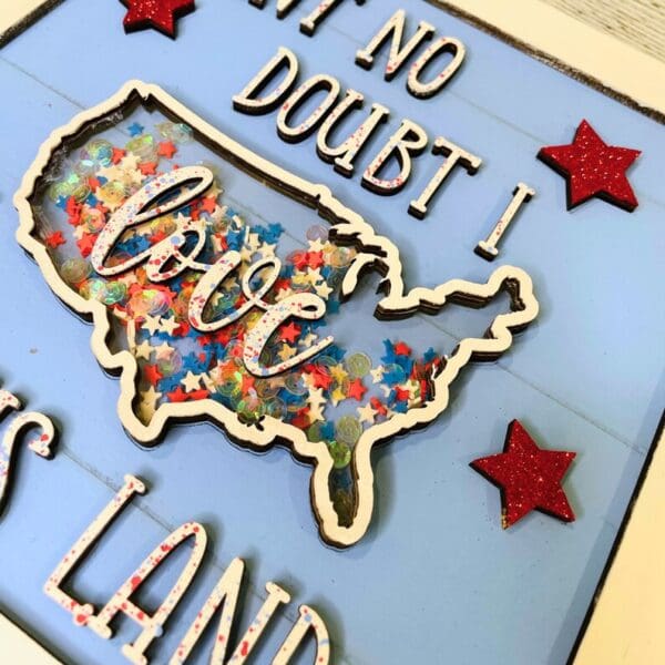 Red Rooster Laser Arts The DIY Patriotic Shaker Sign Kit - Love This Land features a U.S. outline filled with star confetti and love in script, plus red glittery stars and cut-out text on a light blue background.