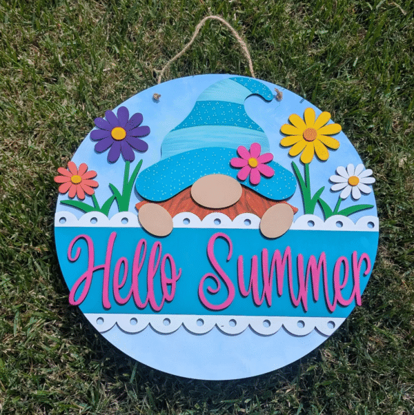 Red Rooster Laser Arts The DIY Door Hanger Kit - Gnome Summer features a round sign with colorful flowers, grass, and a gnome in a blue hat. Hello Summer appears in bold pink—ideal for your next creative door hanger project.