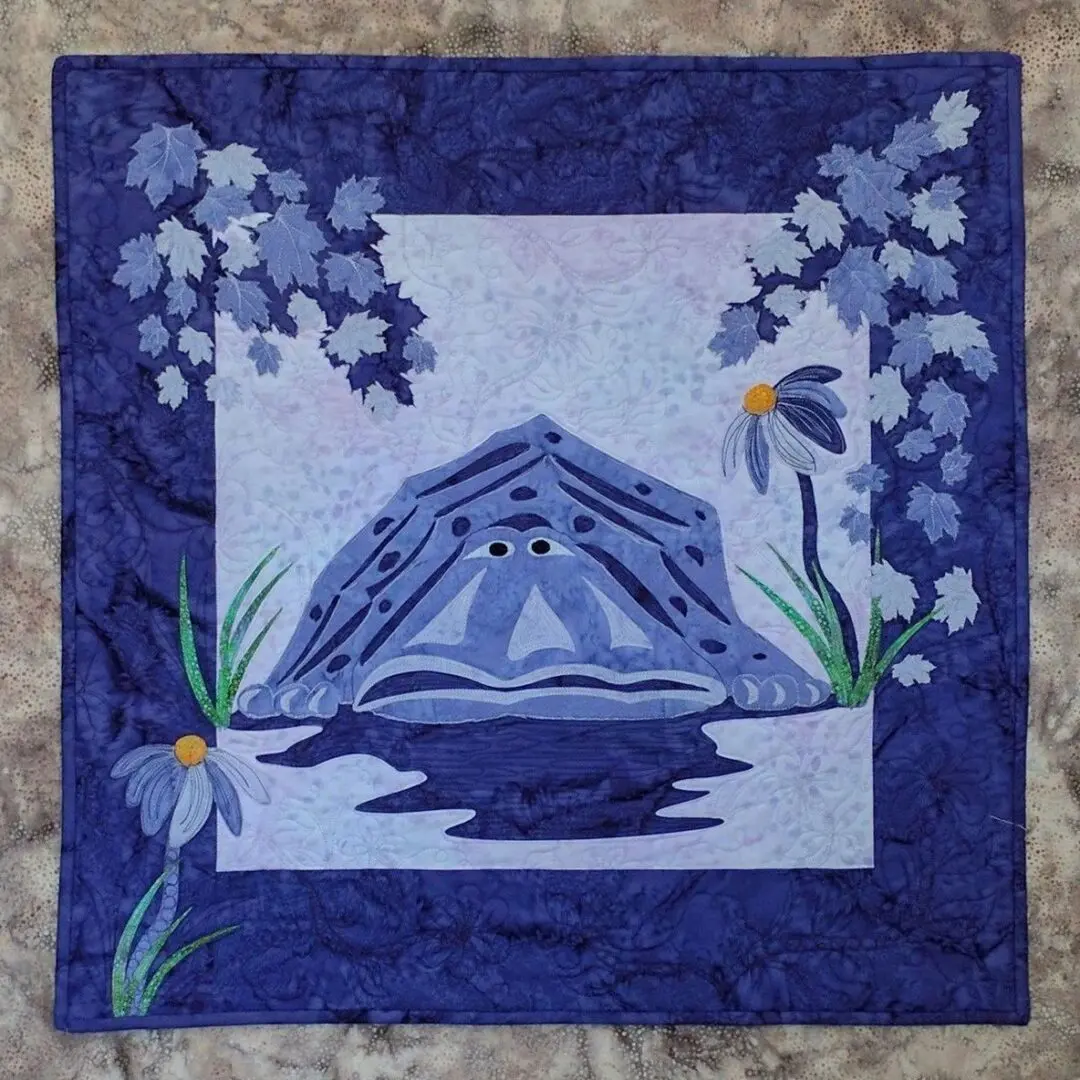 A blue quilt with flowers and a frog