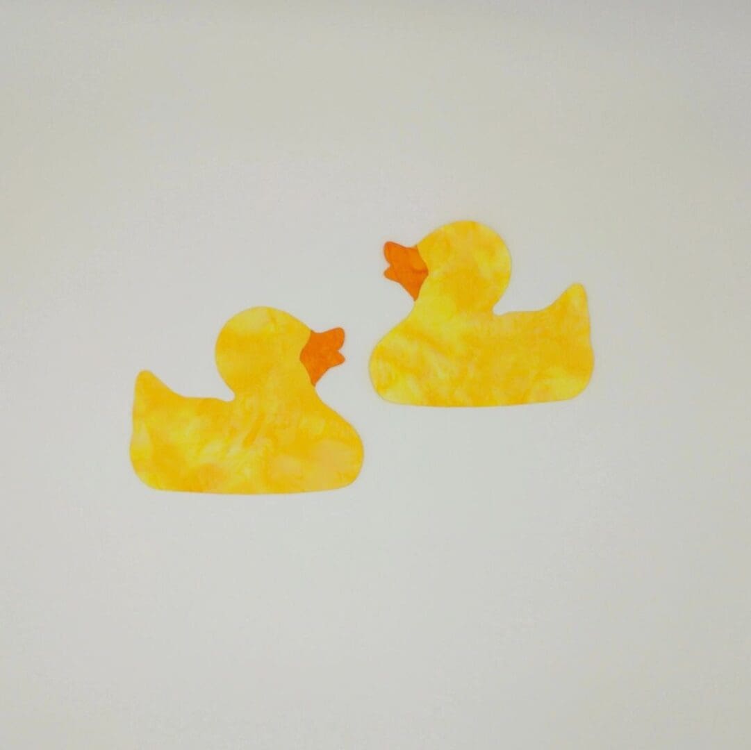 Two yellow rubber ducks on a white surface