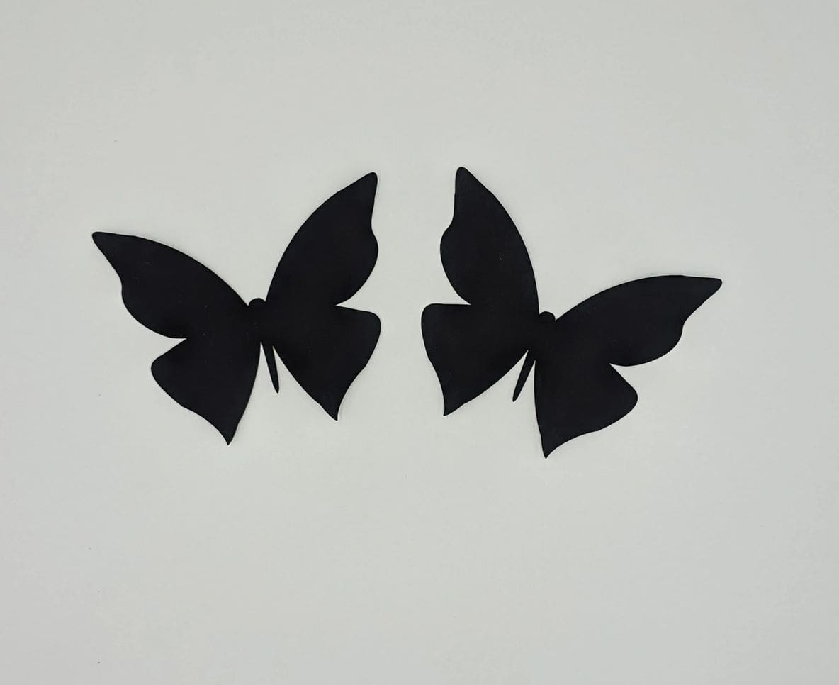 A pair of black butterflies on a white wall.