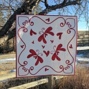 A sign with red hearts on it in the middle of a field.