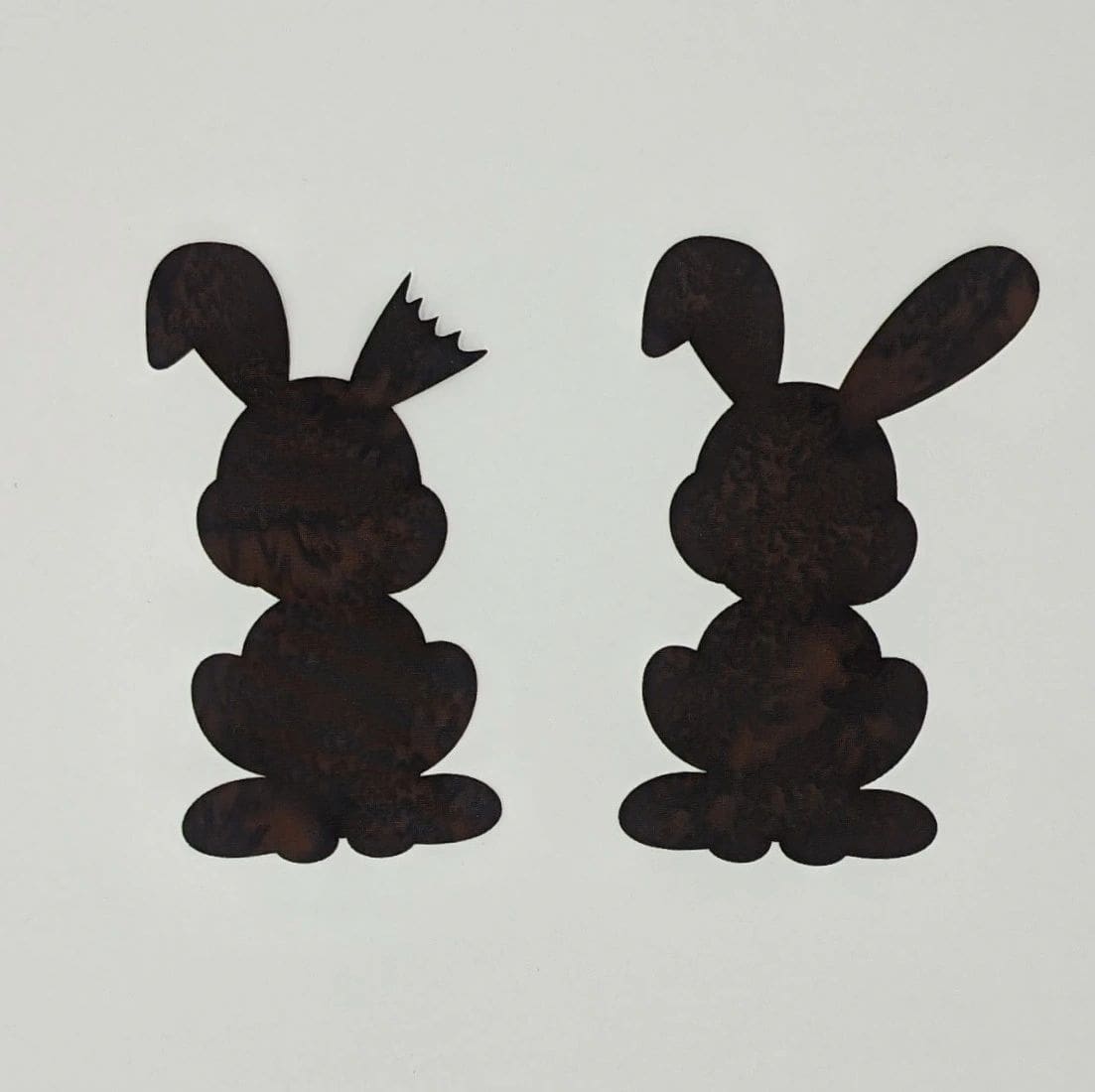 Two black rabbits are sitting next to each other.