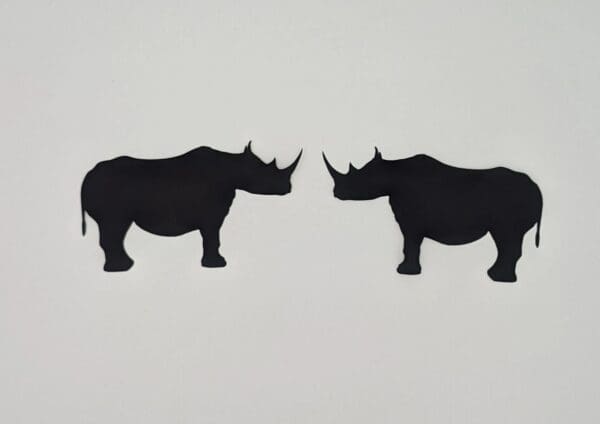 Two black rhinos facing opposite directions in a white background.