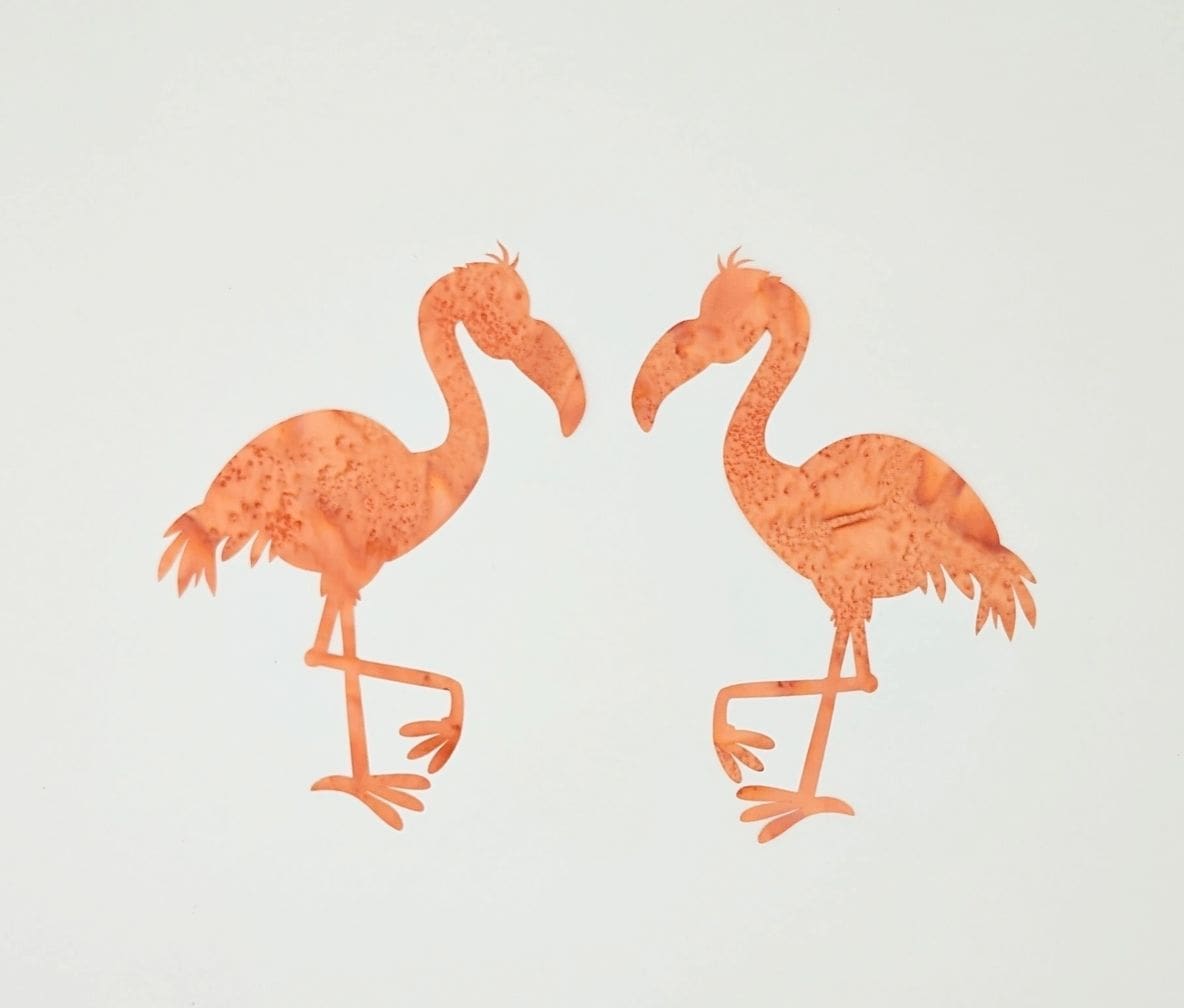 A pair of flamingos are standing next to each other.