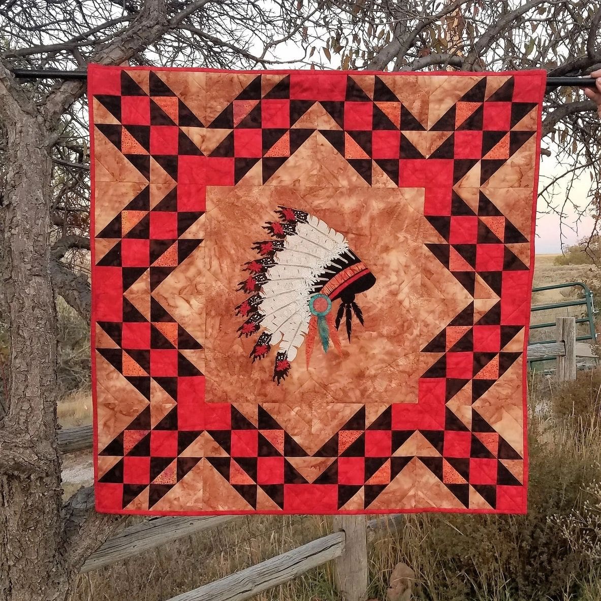 A quilt hanging on the side of a tree.