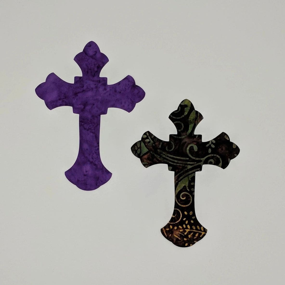 Two crosses are sitting on a white wall.