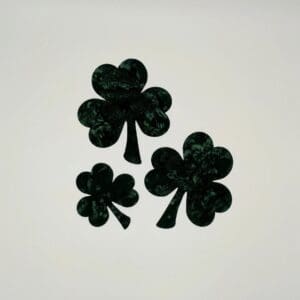 Three black clovers are sitting on a white surface.