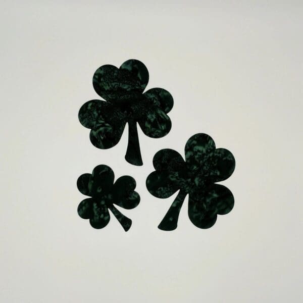 Three black clovers are sitting on a white surface.