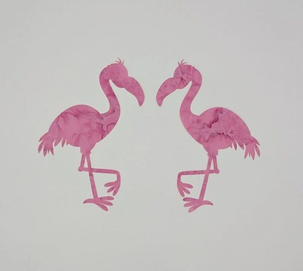 A pair of pink flamingos are standing next to each other.