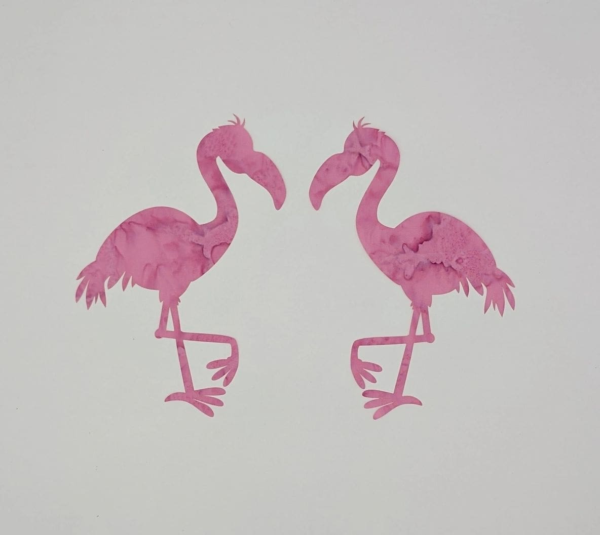 A pair of pink flamingos are standing next to each other.