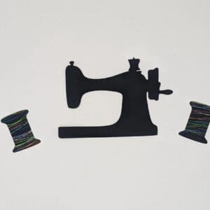 Red Rooster Laser Arts A laser-cut figure of a vintage sewing machine, elegantly accompanied by two spools of colorful prefused thread, is set against a plain white background. These are laser cut and pre fused appliques, made from high quality quilting cotton.