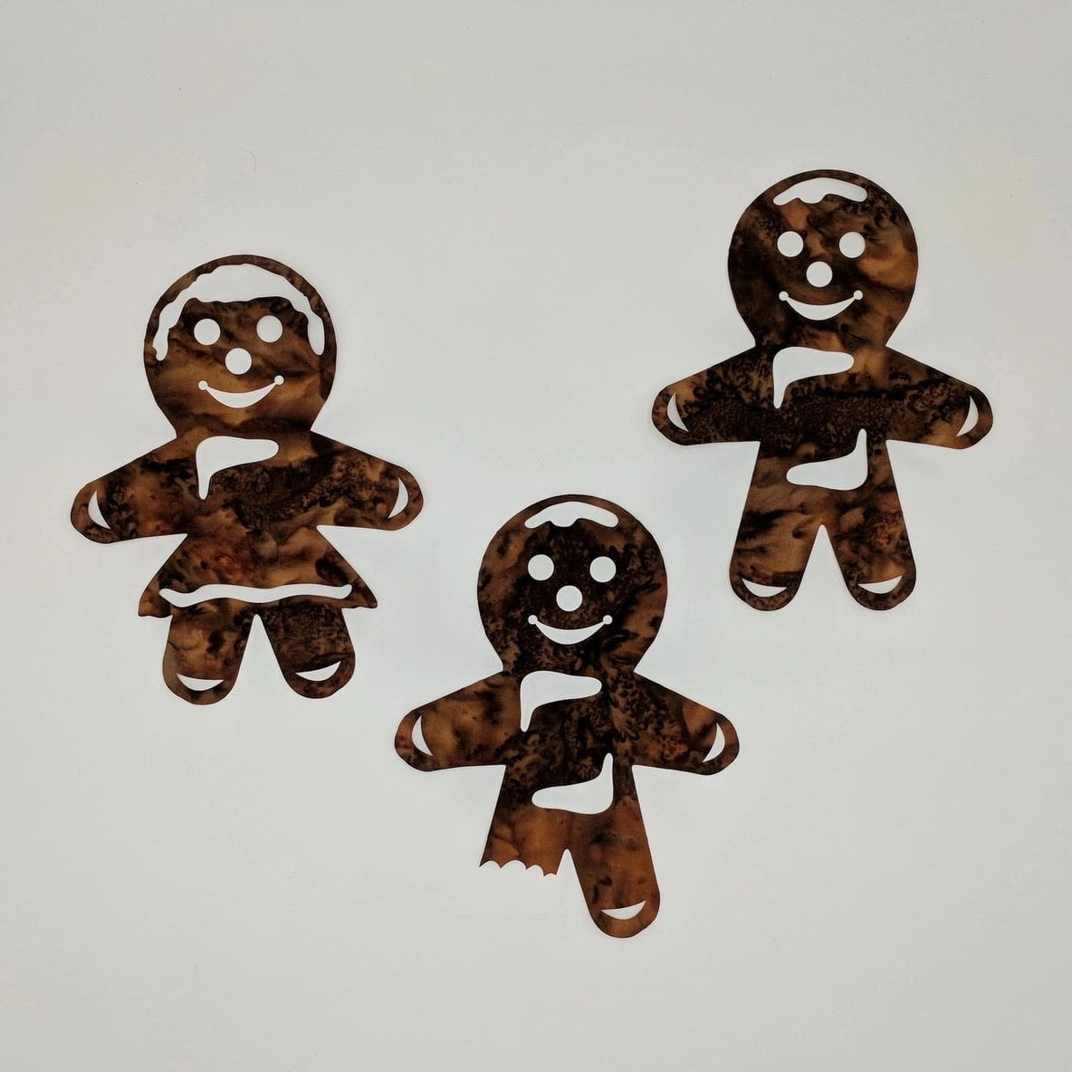 Three small gingerbread men are sitting on a table.