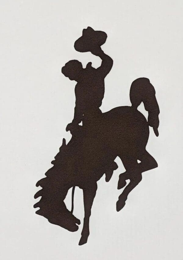 A silhouette of a cowboy riding on the back of a horse.