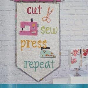 A banner hanging on the wall with sewing themed words.