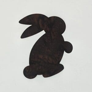 A black rabbit sitting on top of a white wall.