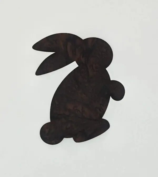 A black rabbit sitting on top of a white wall.