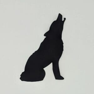 A silhouette of a wolf sitting on the ground.