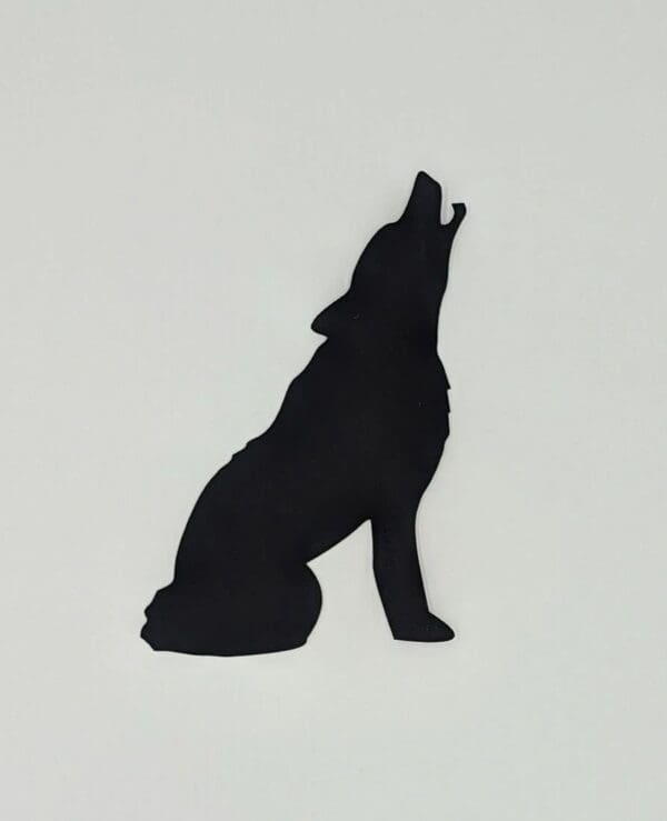 A silhouette of a wolf sitting on the ground.