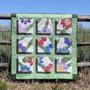 A quilt sitting on top of a wooden fence.