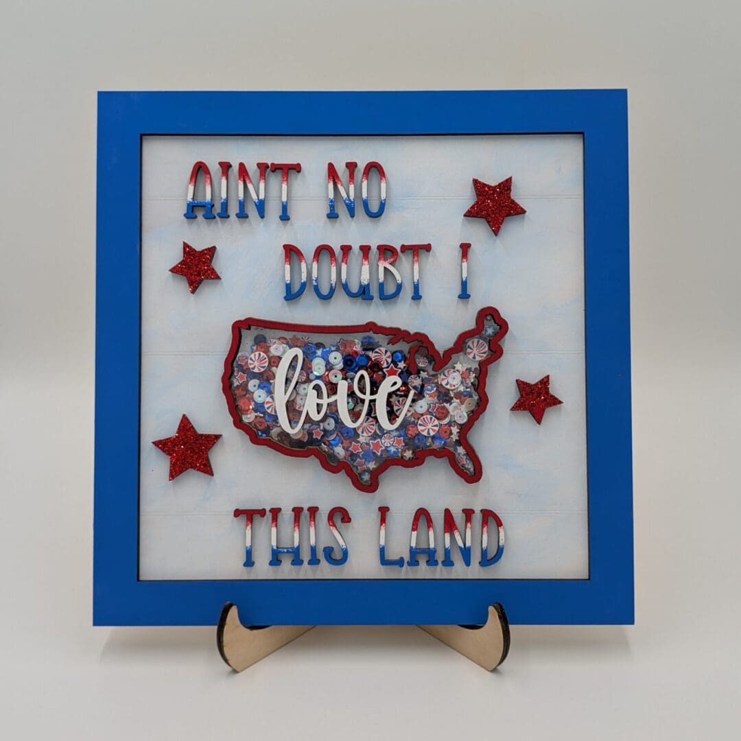 Red Rooster Laser Arts The DIY Patriotic Shaker Sign Kit - Love This Land features a blue border, bold red and blue AINT NO DOUBT! text, and three glittery red stars for a festive, framed look.