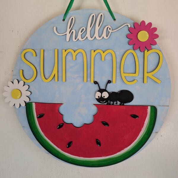 Red Rooster Laser Arts The DIY Door Hanger Kit - Welcome Summer includes a round hanger with hello summer, a cartoon watermelon slice, a smiling black ant, and two colorful flowers—one pink and one white.