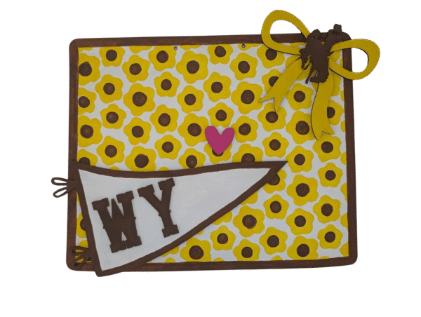 Red Rooster Laser Arts The DIY Door Hanger Kit - Wyoming State features a rectangular hanger with yellow and brown florals, a pink heart center, brown/yellow ribbon with bronco silhouette (top right), and a white WY pennant (bottom left).