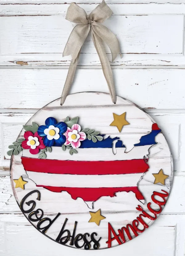 Red Rooster Laser Arts The DIY Door Hanger Kit - God Bless America features a round wooden hanging with a striped U.S. map, gold stars, colorful flowers, burlap ribbon on top, and “God bless America” at the bottom. Perfect for patriotic home décor.