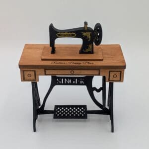 Red Rooster Laser Arts An Antique Singer Sewing Machine Model rests on a wooden table with ornate black legs and gold accents, set against a plain white background.