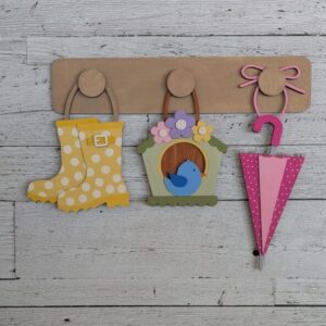 Red Rooster Laser Arts The DIY Interchangeable Wall Peg System Decor - Spring features a wooden hook with three pegs displaying a polka dot rain boot, birdhouse with blue bird, and pink umbrella—ideal for Easter accents on a white wood background.