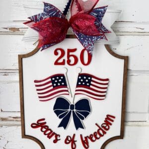 Red Rooster Laser Arts Celebrate America’s 250th with the DIY Door Hanger Kit – "250 Years of Freedom," featuring red, white, and blue ribbons, two American flags, and patriotic text on a white wood background.