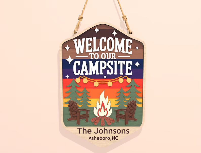 Red Rooster Laser Arts DIY Door Hanger Kit - "Welcome to our Campsite 2" features bold text, colorful trees, string lights, a campfire, two chairs, and includes custom details like names and location. Hang by rope for a personalized camping decor accent.
