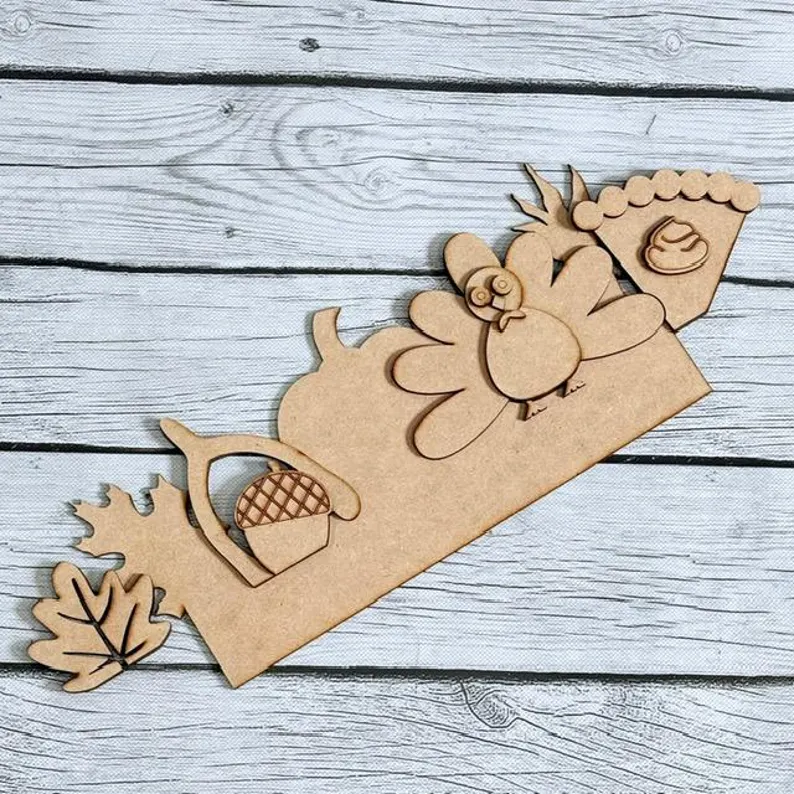 Red Rooster Laser Arts Introducing the "Interchangeable Door Hanger Insert - Fall Coffee Cups (Copy)"—a wooden cutout set featuring a turkey, pie slice, acorn, pumpkin, and leaves arranged on a rustic white wooden background. Perfect for adding to your DIY Fall Coffee Cup door hanger insert kit!.