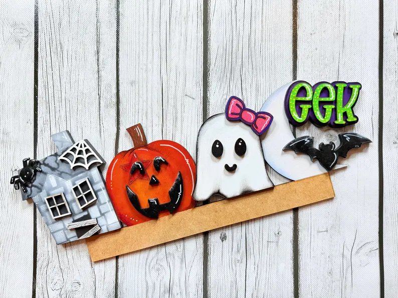 Red Rooster Laser Arts Halloween ruler with decorations: a gray haunted house with spiderweb, carved pumpkin, ghost with pink bow, bat, and green "EEK" text on a wooden background—perfect for pairing with your Interchangeable Door Hanger Insert - Thanksgiving Harvest (Copy) to craft unique seasonal décor.